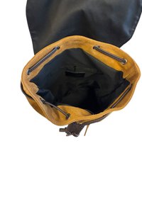 Pokrowiec na sznurku z czarnym materiałem na zewnątrz i brązowym zamszowym wykończeniem. Wnętrze jest czarne z metką. Posiada dwa sznurki i miękką teksturę.