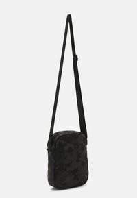 Borsa a tracolla nera con motivo camouflage, con tracolla regolabile, texture morbida e forma rettangolare. Chiusura con zip e design minimalista.