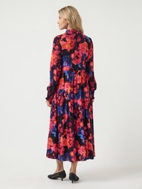 Kwiatowa sukienka maxi w kolorze czarnym, z intensywnie czerwonymi, różowymi i niebieskimi kwiatami. Długie rękawy z falbaniastymi mankietami i warstwowym projektem spódnicy.