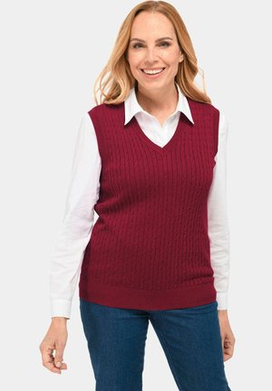 Bordeaux kabelgebreide sweatervest met een V-hals, textuurpatroon en geribde zoom, gedragen over een witte blouse met kraag.