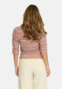 Multicolored cropped top featuring a textured pattern in pink, gold, and white, with three-quarter sleeves and a fitted shape.