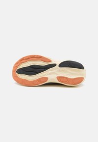 Semelle de chaussure avec un schéma de couleurs noir et crème, présentant un motif texturé de zones rembourrées et des accents orange pour une meilleure adhérence.