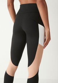 Højtaljede leggings med en sort hoveddel, med nude og hvide paneldetaljer. Glat, strækbart stof med en tætsiddende design.