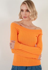 Pulover portocalie cu umerii descoperiți, cu model striat, mâneci lungi și un design ajustat, realizat dintr-un material tricotat texturat.