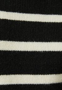 Black and cream striped knit fabric featuring alternating thick and thin horizontal lines with a soft texture.