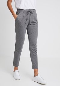 Grå, avsmalnande sweatpants med dragsko i midjan, sidfickor och slät tyg, i kombination med vita sneakers och en vit T-shirt.