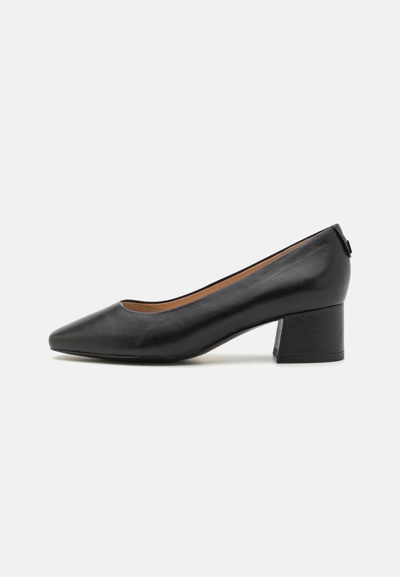 Sandal de couro preto com bico fino e um salto bloco moderado. Textura suave com um design simples e detalhes de hardware mínimos.
