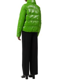 Groene glanzende pufferjack met een hoge kraag, voorzien van gequiltte secties en een relaxte pasvorm, gecombineerd met zwarte wijde broek en hoge laarzen.