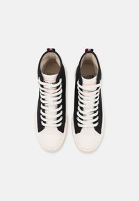 Baskets montantes noires avec semelles en caoutchouc blanches et bout rond. Tige en coton, lacets blancs, et accents rouges et bleus au talon.