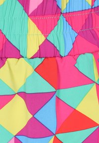 Tessuto multicolore con motivi geometrici in rosa, verde, giallo e blu; presenta una texture arricciata lungo il bordo superiore.