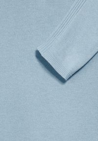 Ljusblå stickad tröja med ribbad ärm. Mjuk textur och lättviktig tyg, med ett jämnt och slätt stickmönster.