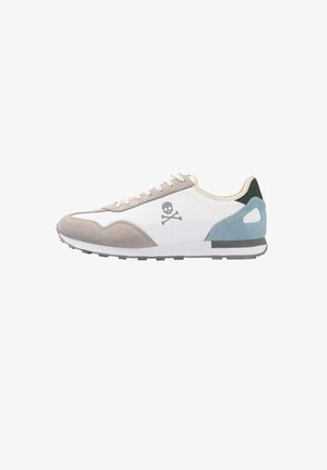 Sneakers mit einem weißen Obermaterial aus Stoff, grauem Wildleder am Zehenbereich, blauen und schwarzen Akzenten, einem Totenkopf-Logo an der Seite und einer strukturierten Gummisohle.