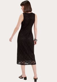 Robe midi en dentelle noire avec une texture à motif en losanges, sans manches, encolure ronde et silhouette droite. Longueur sous le genou.