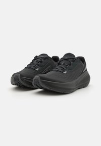 Scarpe da ginnastica nere con tomaia in rete testurizzata, collare imbottito e suola flessibile. Presentano accenti a contrasto e un motivo di battistrada resistente.