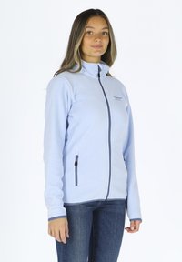 Hellblaues Fleece-Jackett mit hohem Kragen, durchgehendem Reißverschluss und zwei seitlichen Taschen. Verfügt über dunkelblaue Akzente und ein dezentes Logo.