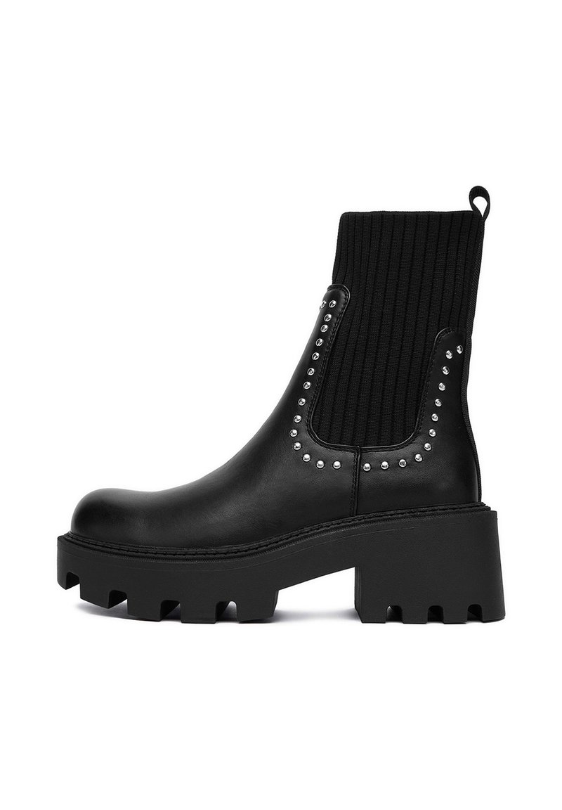Czarny botek do kostki z masywną podeszwą, górą z żebrowanej tkaniny, srebrnymi ćwiekami po bokach oraz strukturalnym wykończeniem.