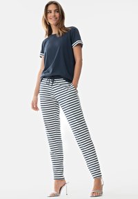 Marineblauwe top met korte mouwen en gestreepte pyjamabroek in het wit en marineblauw. De broek heeft zakken; het materiaal lijkt zacht en heeft een ontspannen pasvorm.