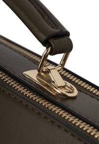 Ruskea nahkainen laukku, jossa on kultainen vetoketju ja metalliset osat. Sen pinta on sileä ja kahva tukevasti rakennettu, ja siinä on metallinen solki.