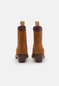 Stivaletti alla caviglia in suede marrone con punta arrotondata, pannelli laterali elasticizzati e tacco a blocco. Presentano dettagli in pelle marrone sul tallone.