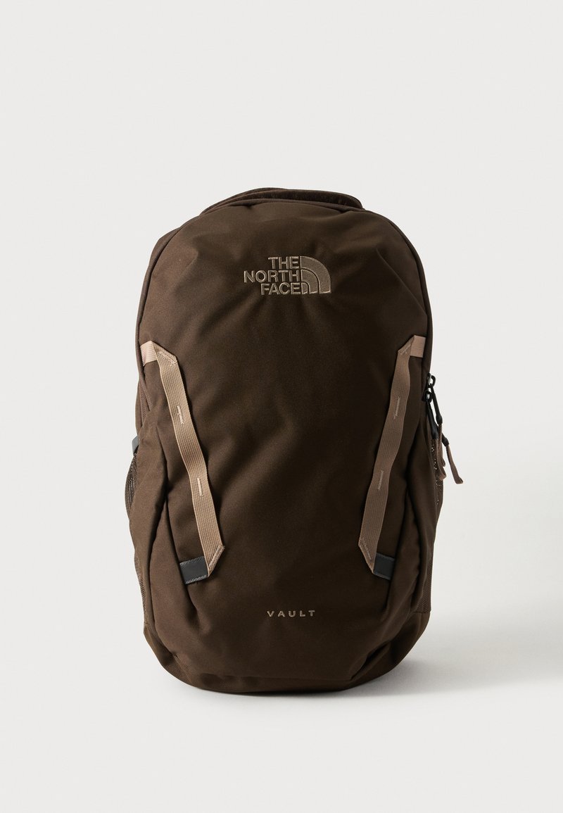 Καφέ σακίδιο North Face Vault με μπεζ κάθετες λουρίδες και λογότυπο μπροστά σε ένα απλό ανοιχτό φόντο.