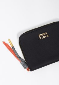 Czarny portfel na zamek z złotym logo marki, z teksturowanym wykończeniem i kolorowymi akcentami w czerwieni i szarości.