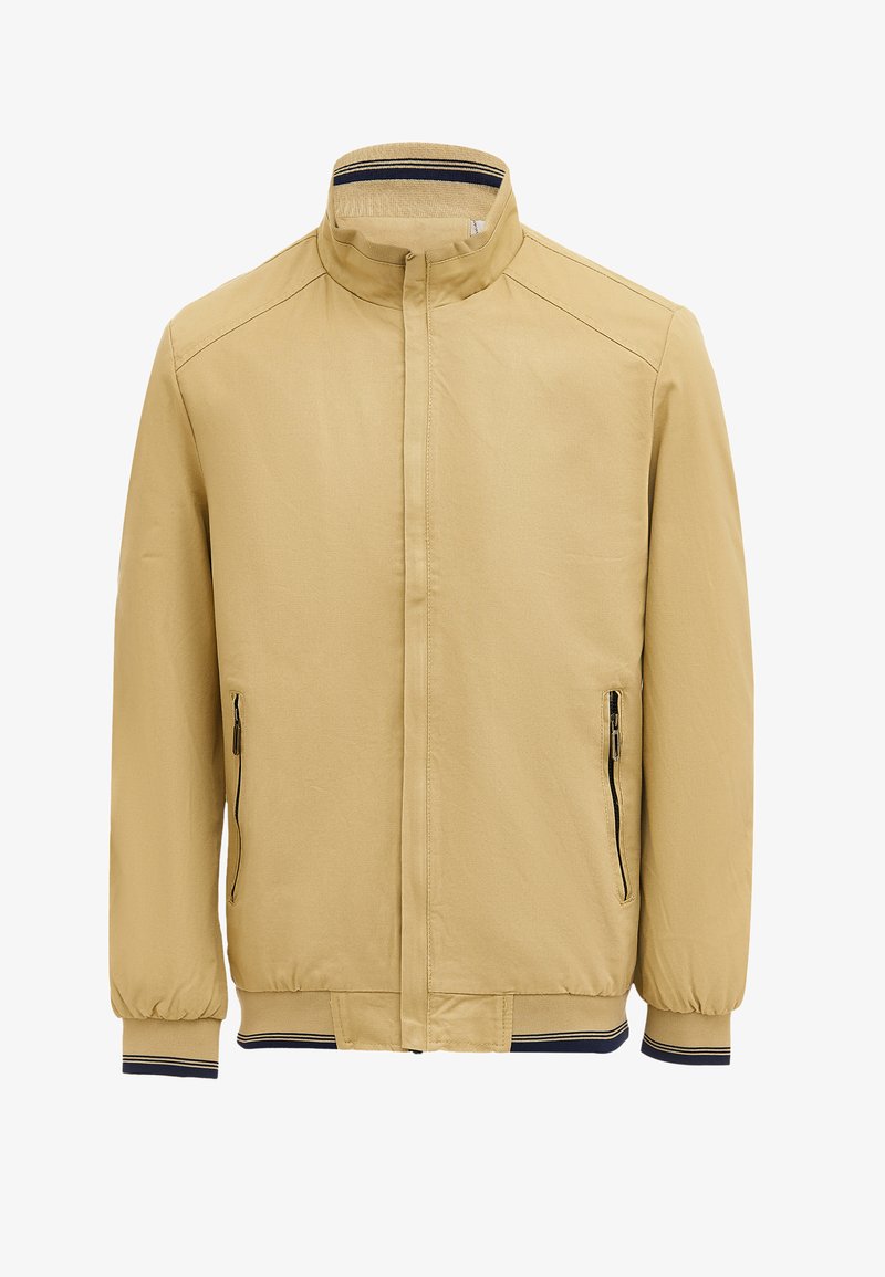 Beige jas met een staande kraag, twee zijzakken met ritsen en ribgebreide manchetten met marineblauwe accenten. Gemaakt van een soepele, lichte stof.