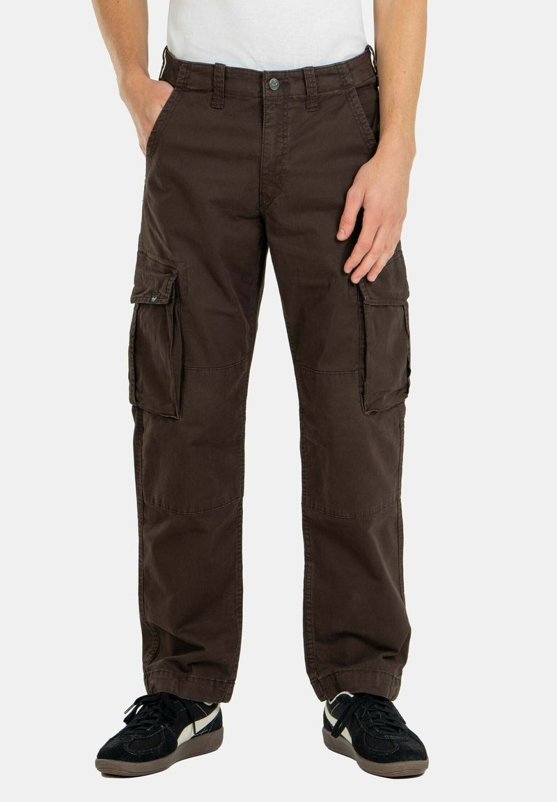 Braune Cargo-Hosen mit mehreren Seiten Taschen, geradem Bein-Design, aus Baumwollmaterial und mit kontrastierenden Nähten. Getragen mit schwarzen Sneakers.
