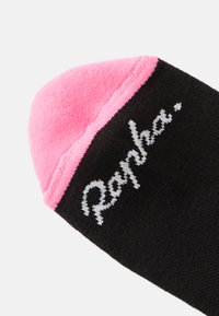 Calcetín negro con un puño rosa, que presenta el logotipo blanco de "Rapha". El material es texturizado, resaltando la comodidad y durabilidad.