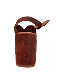 Zapato de tacón alto de ante marrón con una plataforma gruesa, diseño de parte trasera abierta y correa ajustable en el tobillo. Textura suave con un acabado mate.