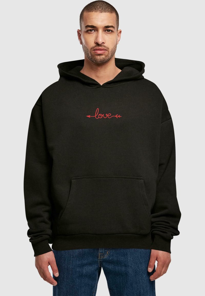 Sort hoodie med en frontlomme, der har rød "love" tekst og pile. Lavet af blødt materiale, med en løs pasform og justerbar hætte.
