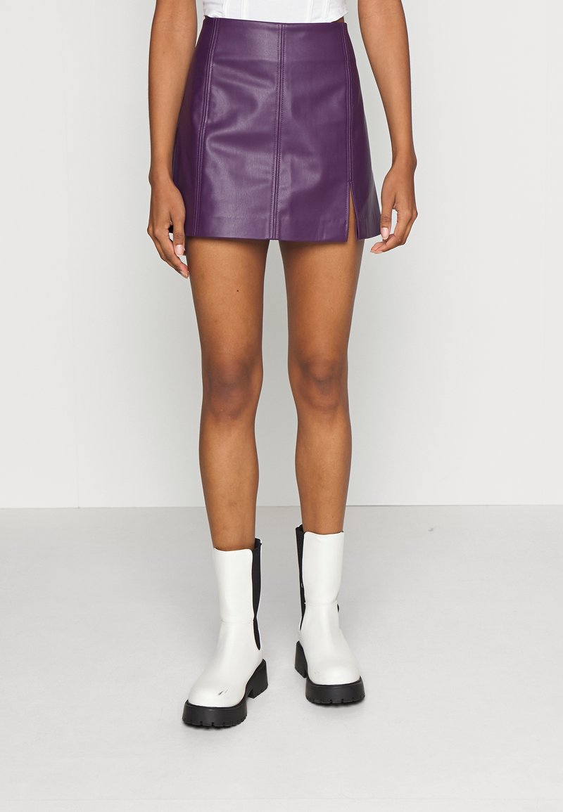 Lila läder mini kjol med en sidosprund, kombinerad med vita och svarta ankelstövlar med en kraftig sula och dragkedjedetalj.