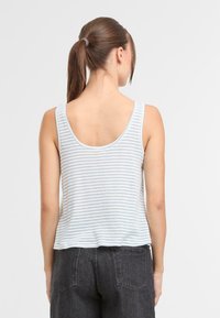 Stribet tanktop i lyseblå og hvid, lavet af blødt stof. Har rund halsudskæring og en afslappet pasform. Parret med mørke jeans.