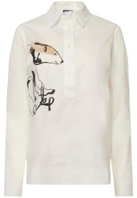 Blusa bianca in cotone con colletto e patta con bottoni. Presenta un'illustrazione animale astratta nera e beige distintiva sulla parte anteriore.