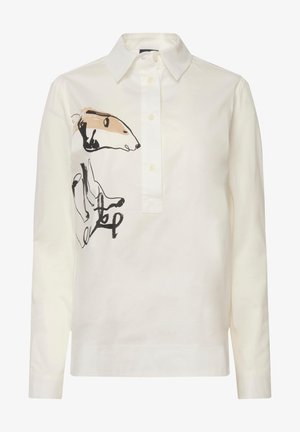 Biała bawełniana bluzka z kołnierzykiem i zapięciem na guziki. Z przodu znajduje się charakterystyczna czarno-beżowa abstrakcyjna ilustracja zwierzęcia.