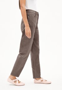Gray cotton jeans with a straight-leg cut and front pockets, paired with light pink closed-toe shoes featuring cut-out details.