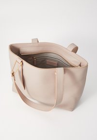 Beige bőr bevásárlótáska strukturált felülettel, kettős válltartóval és cipzáros zsebbel belül. Minimális dizájn, látható fém alkatrészek nélkül.