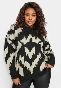 Maglione oversize nero e crema con motivo geometrico a zigzag, colletto a coste e maniche lunghe, realizzato in materiale lavorato a maglia testurizzato.