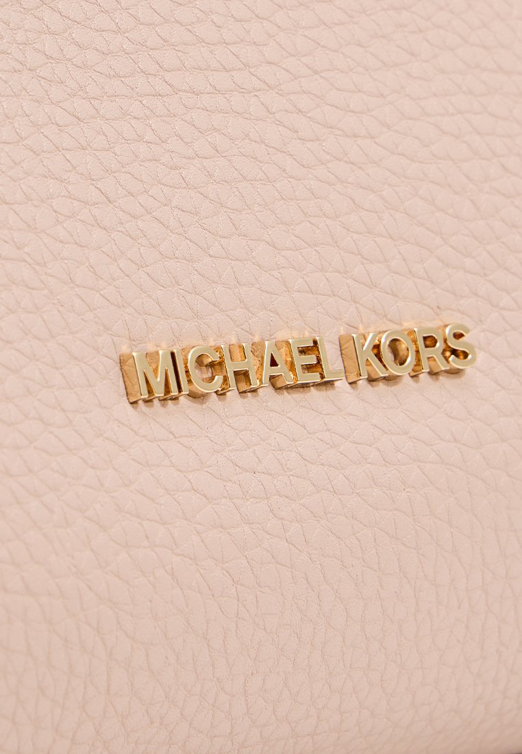 Roze textuurleer met gouden "MICHAEL KORS" logo. Heeft een subtiele nerfpatroon en toont een zachte en gladde afwerking.