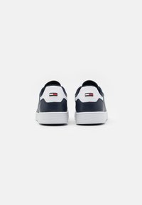 Sneakers blu navy con accenti bianchi, tomaia in pelle liscia, suola in gomma e dettaglio del logo sul retro, dotati di un tallone imbottito.