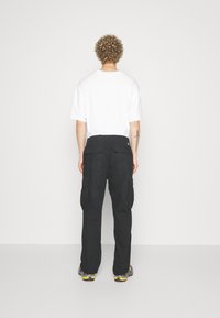 Svarta cargobyxor med sidofickor, matchade med en vit oversized t-shirt. Tyget verkar vara rikligt på bomull, med en avslappnad passform och rak ben.