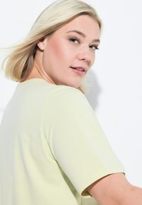 Maglietta gialla chiara a maniche corte con scollatura arrotondata, texture liscia e design semplice. Presenta una vestibilità comoda e cuciture sottili.