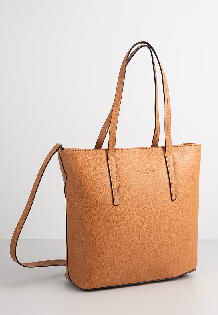 Borsa tote in pelle tan con manici lunghi, forma rettangolare elegante e chiusura con zip. Texture liscia e design minimalista con logo impresso.