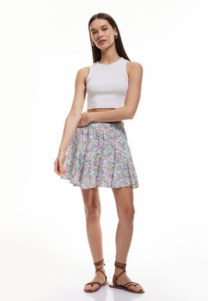 Hame skirt bercorak bunga dengan desain mengembang, menampilkan bunga merah muda dan biru di latar belakang yang terang. Dipadukan dengan atasan crop putih yang pas.