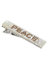 Hårklämma med en blank krämfärg, pryds av ordet "FRID" i bruna rhinestones. Silverfärgad metallklämma med räfflade kanter.