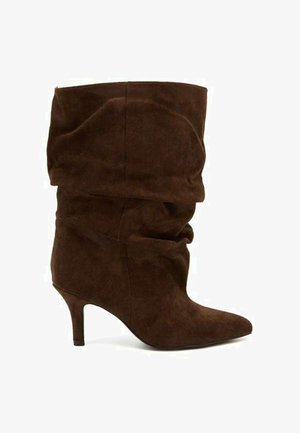 Botte en daim marron mi-mollet avec bout pointu et talon fin type kitten sur fond blanc.