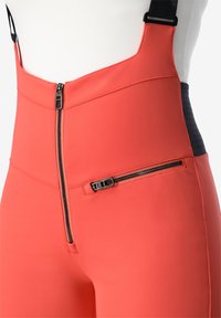  Hoog getailleerde koraalkleurige broek met een rits aan de voorkant, een zijritszak en verstelbare zwarte schouderbanden. Glad materiaal met een gestructureerd achterpand.