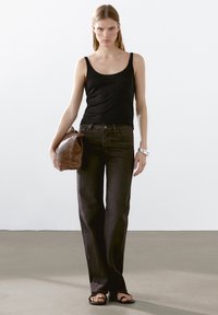 Svart ärmlös topp, mörkgrå raka jeans, vävd brun clutchväska och svarta platta sandaler. En enkel, avslappnad outfit med rena linjer.