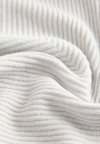 Tela gris claro tejida con una textura acanalada. El material muestra costuras finas y una apariencia suave, ligeramente elástica.