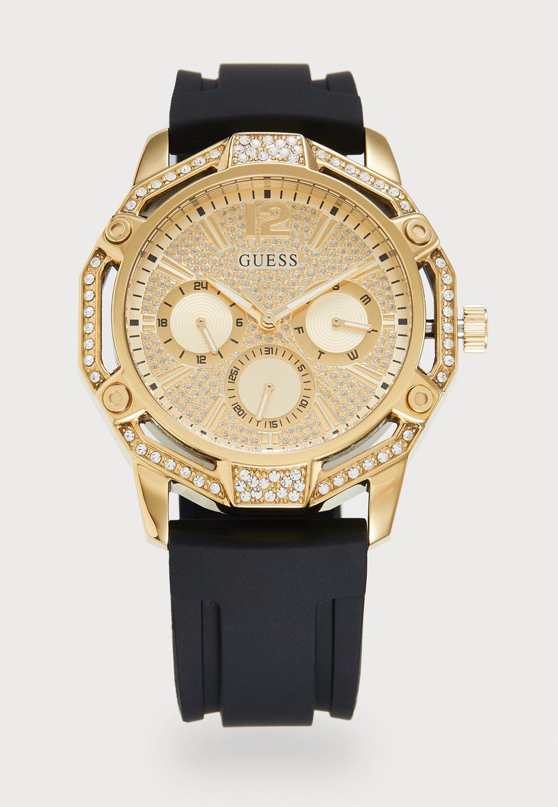 Montre Guess dorée avec un cadran et une lunette ornés de cristaux, bracelet en silicone noir, trois sous-cadrans pour les fonctions 24 heures, jour et date.