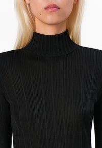 Black ribbed turtleneck sweater featuring a high collar and textured fabric, showcasing vertical stripes and a fitted silhouette.